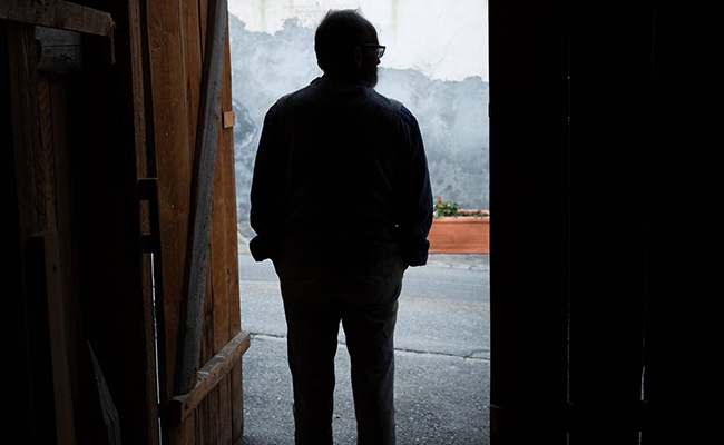 Ein Mann steht im Eingang einer Scheune und blickt nach draussen.